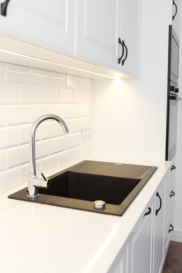 biała kuchnia z czarnym AGD, płytkami metro i blatami w połysku – profesjonalna fotografia wnętrz kuchennych