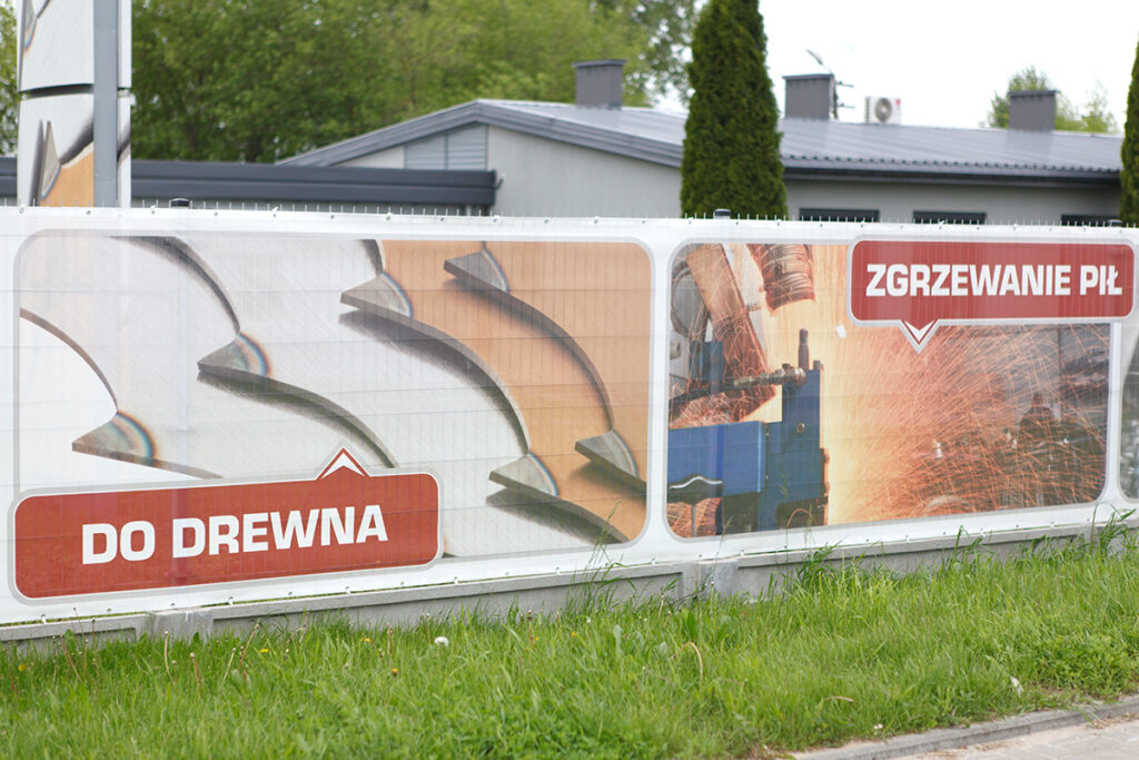 Detal banera „do drewna” z grafiką pił taśmowych – zdjęcie reklamowe outdoor dla branży maszynowej