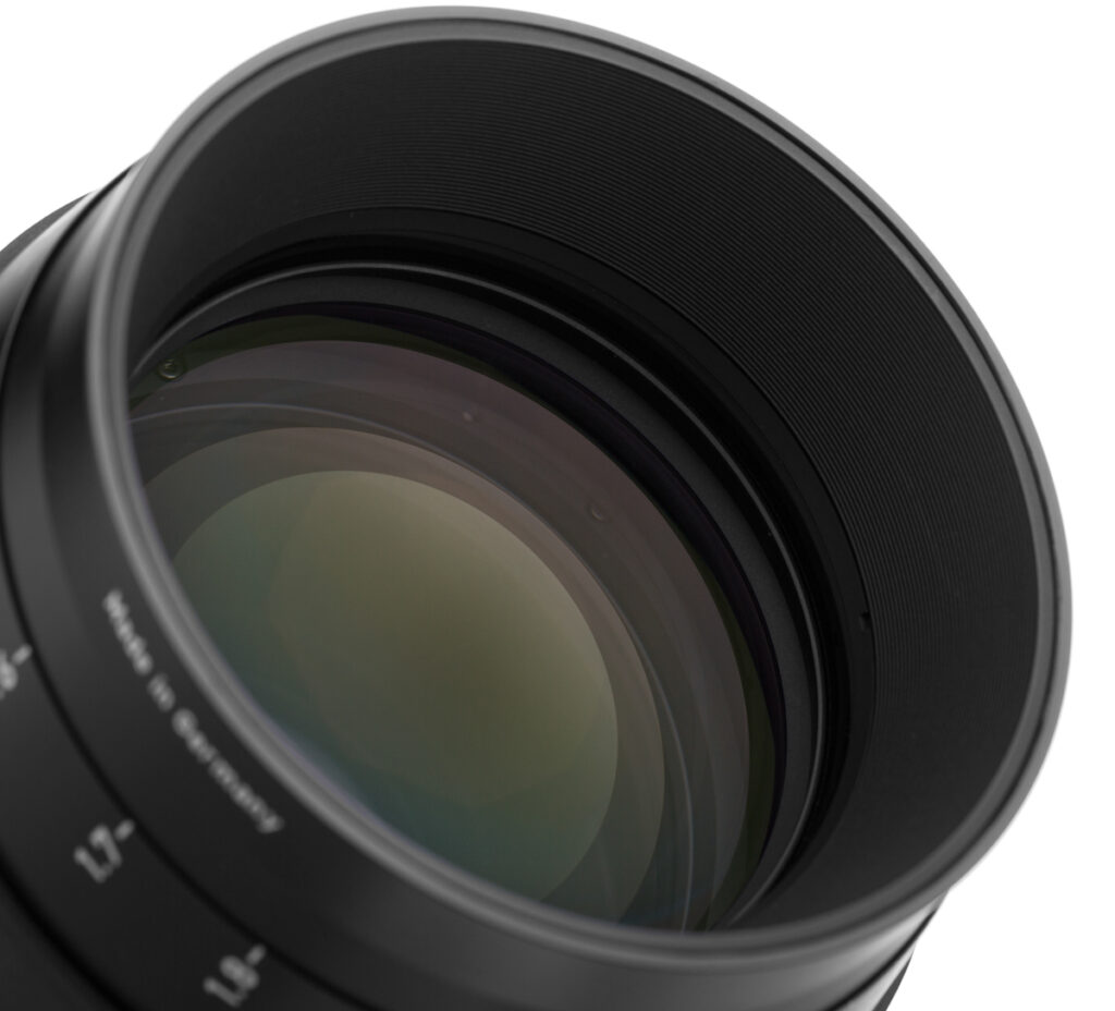 Packshot obiektywu – zbliżenie przedniej soczewki z zielonymi refleksami powłok, fotografia produktowa sprzętu foto