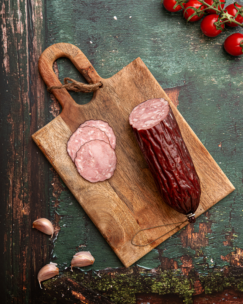 Fotografia potraw na desce: salami rzemieślnicze w stylu rustykalnym.